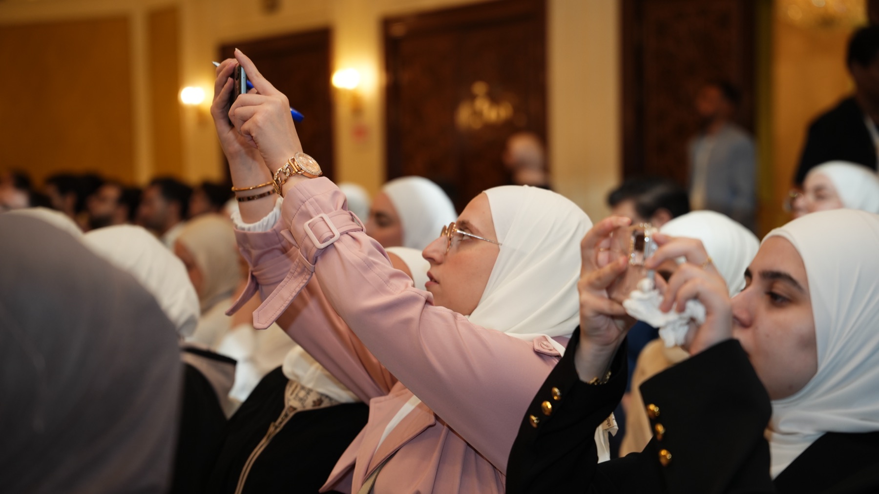 حاضرات في مؤتمر إكسيد للنمو على لينكدإن يوثقن إحدى الجلسات بهواتفهن